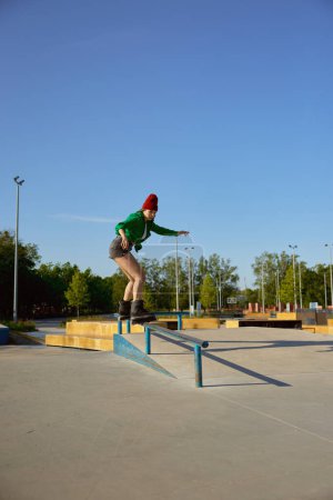 Foto de Hembra concentrada practicando acrobacias y trucos en una rampa especial en un parque deportivo urbano - Imagen libre de derechos