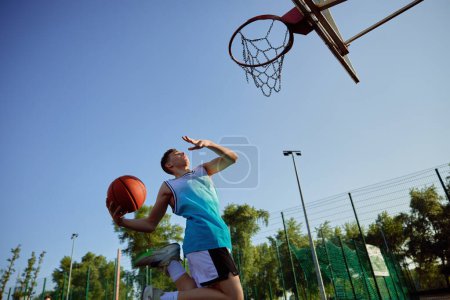 Photo for Teenager aiming into basketball hoop playing on playground. Street outdoors activity and sport for children - Royalty Free Image