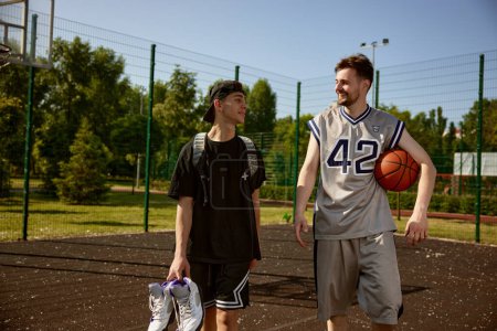 Photo for Trainer and teenager boy talking after practicing basketball on street court. Hobby, active lifestyle, sport activity - Royalty Free Image