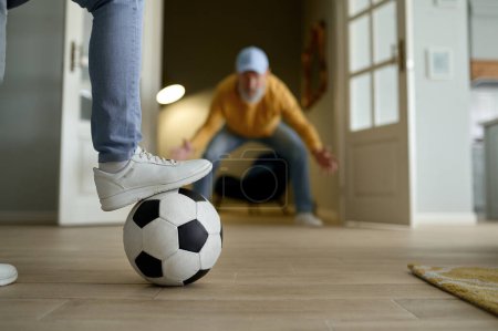 Photo for Happy married couple of retiree playing football. Selective focus of female foot on soccer ball and concentrated senior man in invisible gate on blurred background - Royalty Free Image