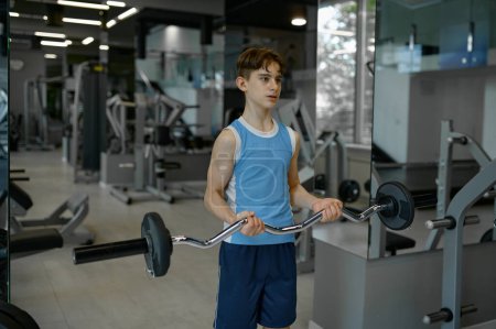 Photo for Strong teenager boy training himself exercising with barbell at gym club. Children sport and health concept - Royalty Free Image