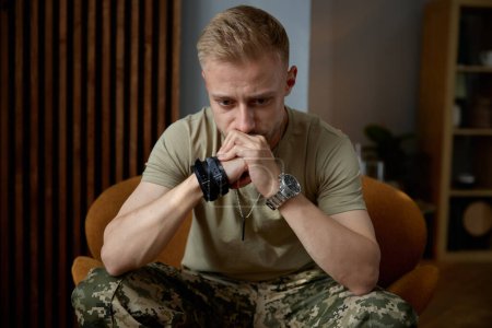 Photo for Portrait of military man being deep in thoughts feeling sorrowful and loneliness sitting on chair at psychologist office. Mental disorder and ptsd symptom - Royalty Free Image