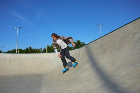 Foto de Adolescente con patines de ruedas que realiza extrema pared-paseo elemento en skate park en verano - Imagen libre de derechos
