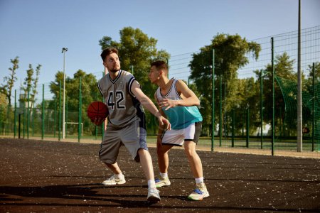 Foto de Hombres activos jugando baloncesto en la cancha callejera. Deportes y pasatiempo recreación para amigos en fin de semana - Imagen libre de derechos