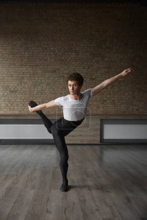 Foto de Bailarín de ballet contemporáneo posando para cámara realizando rutina de estiramiento corporal. Estudio de danza moderna - Imagen libre de derechos