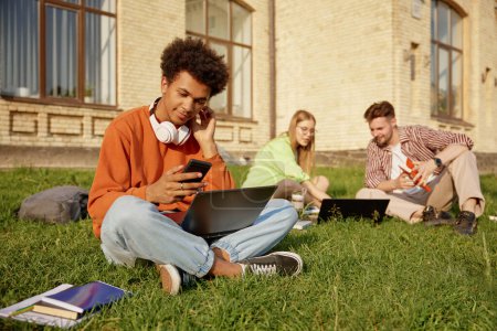 Photo for Group of teenager students studying with laptops, learning for exams and communicating sitting on ground at campus. Free academic education - Royalty Free Image