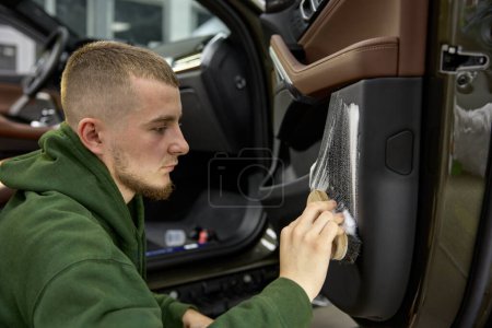 Photo for Car detailing process. Closeup male worker cleaning vehicle door with brush and foam detergent - Royalty Free Image