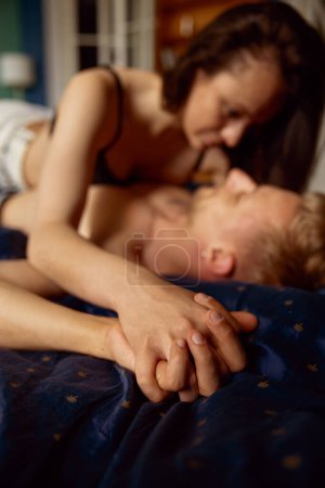 Photo for Passionate beautiful couple having sex in bed. Focus on hands folded together. Intimate relationship concept - Royalty Free Image