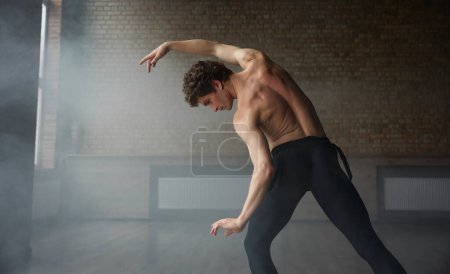Foto de Bailarín masculino de ballet atlético elegante demostrando la parte superior del cuerpo perfecta fuerte. Shirtless musculoso hombre danza performer vista desde atrás - Imagen libre de derechos
