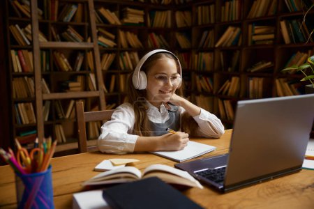 Foto de Feliz niña estudiante que estudia en línea utilizando el ordenador portátil. Concepto de educación en el hogar y educación a distancia - Imagen libre de derechos