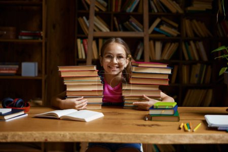 Photo for Back to school concept. Happy little schoolgirl leaning on stack on textbooks ready to study hard on remote lessons of virtual classroom platform - Royalty Free Image