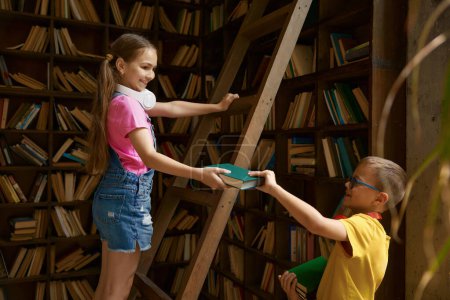 Foto de Los niños están de guardia guardando libros en casa o en la biblioteca escolar. Relaciones familiares entre hermanos o escolares buen comportamiento - Imagen libre de derechos