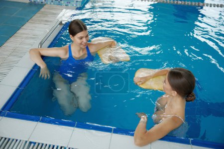 Photo for Friendly smiling women talking and laughing together in swimming pool. Female swimmer friend feeling happy and having nice conversation with humor after training exercise - Royalty Free Image