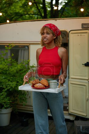 Foto de Chica joven sirviendo mesa con panadería cocinada para picnic al aire libre. Amigos camping partido en trailer van concepto - Imagen libre de derechos