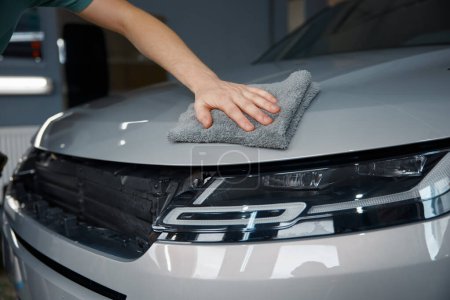 Photo for Process of polishing car body after polymer protective outer covering. Closeup on technician hands holding towel - Royalty Free Image
