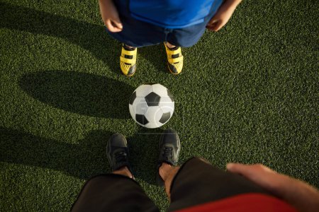 Téléchargez les photos : Père et fils enfant jouant au football sur un terrain extérieur. Focus sur les pieds des joueurs de soccer adultes et jeunes - en image libre de droit