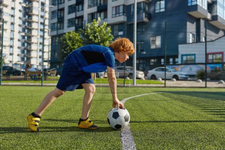 Photo for Concentrated schoolboy child putting ball on strip line on football field. Start soccer game match concept - Royalty Free Image