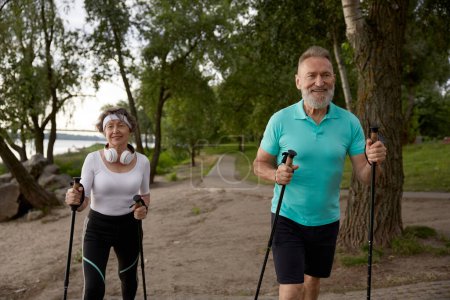 Foto de Mujer anciana y hombre casado pareja disfrutando de polo nórdico caminar ejercicio al aire libre en parque de la ciudad - Imagen libre de derechos