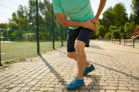 Téléchargez les photos : Sportif senior souffrant d'une blessure au genou pendant l'entraînement de jogging. Entorse ligament ou ménisque problème de santé des personnes âgées - en image libre de droit