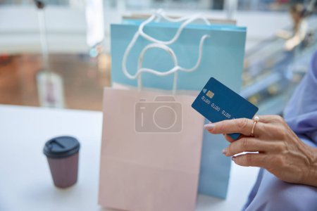 Téléchargez les photos : Closeup main senior femelle tenant la carte de crédit pour le shopping paiement sans contact. Finances, sécurité et encaissement pour les achats - en image libre de droit