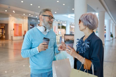 Photo for Retired people spending time in city shopping center. Elderly wife shopaholic asking loving husband for more purchases - Royalty Free Image