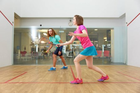 Photo for Couple holding squash racquets playing game match at fitness studio. Athletic man and woman recreation - Royalty Free Image