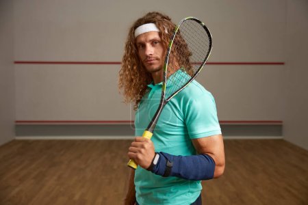 Photo for Portrait of confident male squash player standing with racket ready for game looking confidently at camera - Royalty Free Image