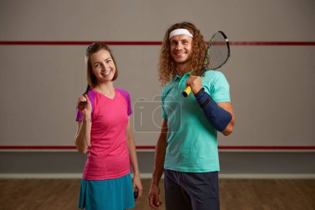 Téléchargez les photos : Heureux joueur de squash masculin et féminin souriant avec portrait de raquettes. Concept de jeu de Racquetball - en image libre de droit