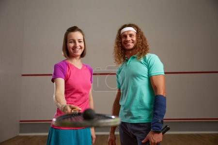 Téléchargez les photos : Couple heureux posant pour la caméra après jeu de squash. Motivation et effort concept de formation - en image libre de droit