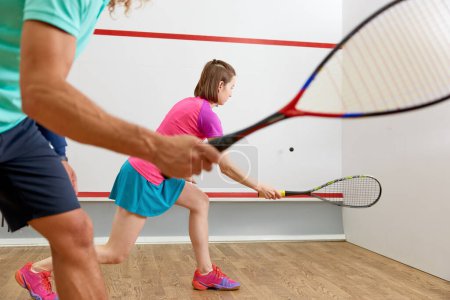 Téléchargez les photos : Jeunes gens jouant au squash profitant de la poursuite récréative au club d'entraînement intérieur. Activité de loisirs en couple le week-end. Vue rapprochée - en image libre de droit