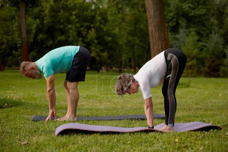 Foto de Feliz pareja mayor haciendo ejercicio de estiramiento al aire libre. Entrenamiento de jubilados para la salud - Imagen libre de derechos
