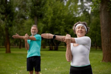Téléchargez les photos : Couple de personnes âgées faisant des exercices d'échauffement pendant un cours de physiothérapie sur la nature. Retraité actif de la famille mode de vie sain - en image libre de droit