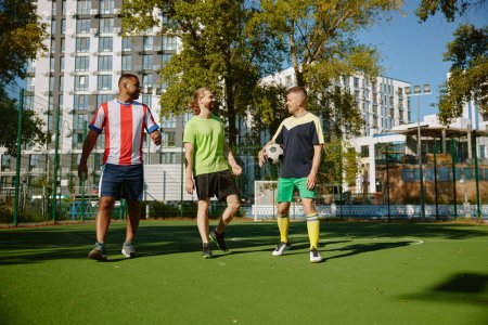 Photo for Smiling male friends walking along on soccer field. Street football players team after training match - Royalty Free Image