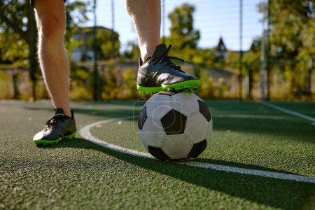 Téléchargez les photos : Gros plan pied mâle en bottes sur le ballon de football sur fond de champ d'herbe verte. Activité sportive de plein air pour adultes - en image libre de droit