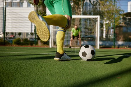 Photo for Closeup football player aiming soccer ball trying to score goal into gate defended by goalkeeper. Active summer holiday outdoor and sport match between friends - Royalty Free Image