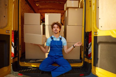 Photo for Courier meditating to keep calm mind holding parcel box in hand while sitting inside delivery truck - Royalty Free Image