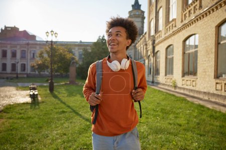 Téléchargez les photos : Portrait d'un adolescent sorti marchant parmi les bâtiments du campus universitaire. Retour au processus d'éducation hors ligne - en image libre de droit