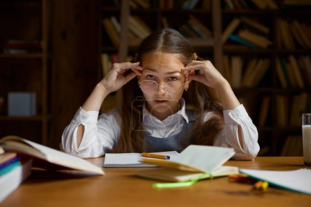Photo for Closeup portrait of smart girl elementary school pupil feeling bored and tired while doing homework - Royalty Free Image