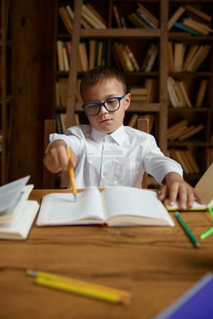 Photo for Little exhausted tired boy schoolchild falling asleep while doing homework at home library. Unhappy smart elementary school pupil feeling depressed and fatigue - Royalty Free Image