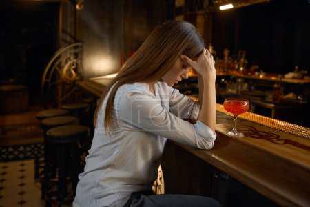 Foto de Mujer solitaria y deprimida sentada en el bar con un cóctel sintiéndose deprimida e infeliz. Problema con el abuso de alcohol - Imagen libre de derechos