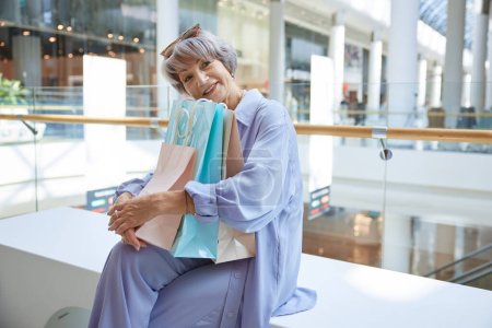 Foto de Feliz mujer mayor satisfecha sosteniendo un montón de bolsas de compras con compras. Concepto de venta, consumismo y jubilados - Imagen libre de derechos