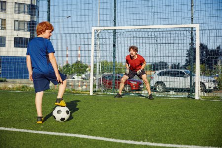 Photo for Father goal keeper and boy son forward training football at stadium. Active family having fun outdoors enjoying sport leisure time - Royalty Free Image