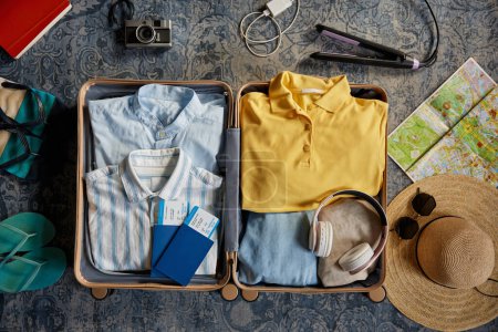 Téléchargez les photos : Valise remplie de vêtements, chaussures et effets personnels pour le voyage. Sac à bagages homme et femme avec kit de vacances - en image libre de droit