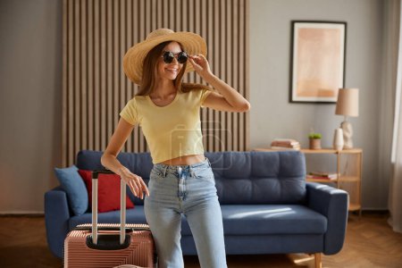Photo for Young woman going for trip, vacation time start, beginning of resort tour on holidays concept. Young gorgeous woman wearing straw hat and sunglasses posing on packed suitcases luggage - Royalty Free Image