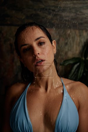 Téléchargez les photos : Passionnée belle femme avec les cheveux mouillés en pose érotique debout sous la pluie de douche tropicale - en image libre de droit