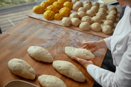 Photo for Closeup view on baker hands preparing formed bread dough for proofing at bakery. Process of baking baguettes - Royalty Free Image