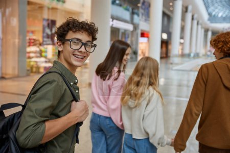 Foto de Retrato de adolescente feliz dando la espalda mientras camina con amigos en el centro comercial. Tiempo feliz juntos y concepto de amistad - Imagen libre de derechos