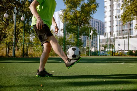 Photo for Sportsman tapping on his ankle while training at city football court cropped shot. Weekend recreation sport activity for adults - Royalty Free Image