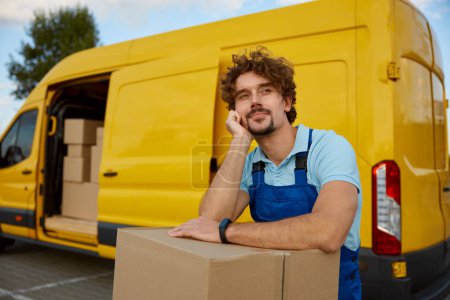 Photo for Portrait of courier enjoying rest leaning at parcel box stack. Logistics expert providing commercial delivery service - Royalty Free Image