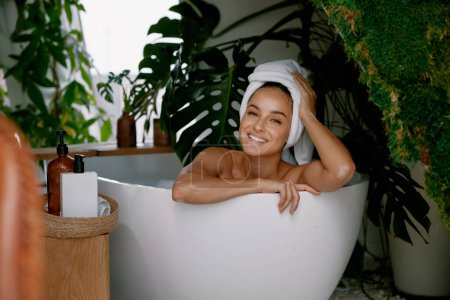 Foto de Retrato de mujer hermosa con la cara clara relajante en la bañera. Cosméticos orgánicos naturales para preservar la juventud y la belleza - Imagen libre de derechos